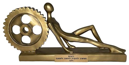 פסל איש יושב נשען על גלגל שיניים מוזהב