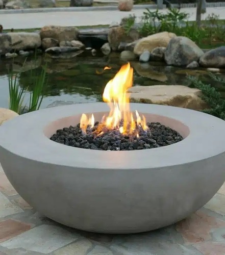 שולחן אש Lunar Bowl עגול עשוי בטון יצוק בשילוב סיבי זכוכית, עם להבות חיות על גבי סלעי לבה דקורטיביים, בקוטר 107 ס