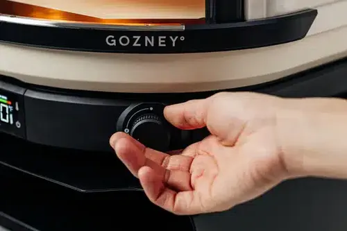 טאבון גז Gozney Arc בעיצוב מודרני וקומפקטי, עם מבער גז ייחודי בעל להבה צידית מתגלגלת, מד טמפרטורה דיגיטלי ושטח בישול מרווח לאפיית פיצות, לחמים וצלייה בחום גבוה.