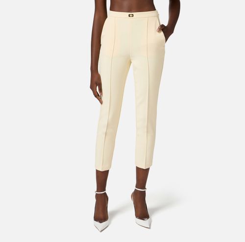 Trousers in crêpe fabric with pockets and logo plaque