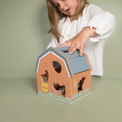 ילדה משחקת במשחק התאמת צורות מעץ של Little Dutch בצורת בית חווה
