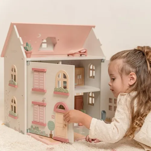ילדה משחקת בבית בובות מעץ עם רהיטים של ליטל דאץ'