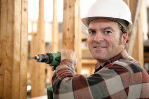 A carpenter using a battery powered drill on a construction site.