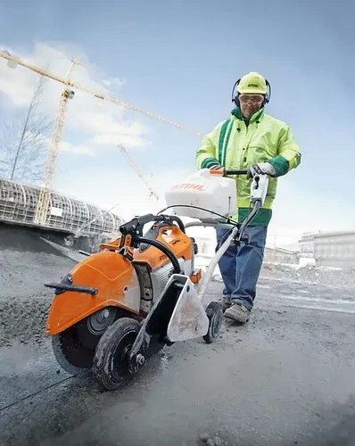 עובד באתר בנייה מפעיל מסור דיסק STIHL המותקן על עגלת חיתוך FW 20, לחיתוך מדויק של בטון ואספלט