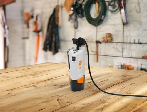ספק כוח נייד STIHL PS 1 מוצב על שולחן עץ בסדנה עם כלי עבודה ברקע