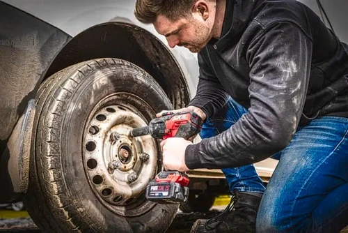 טכנאי משתמש במפתח רטיטה נטען SKIL 20V לפתיחת אומי גלגל רכב