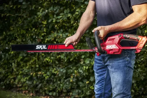 גוזם גדר חיה נטען SKIL 20V בפעולת גיזום גדר חיה בגינה פרטית