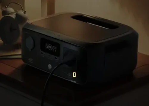 תחנת כוח EcoFlow RIVER 3 UPS בשימוש ביתי על שידה עם חיבור לחשמל בזמן גיבוי UPS