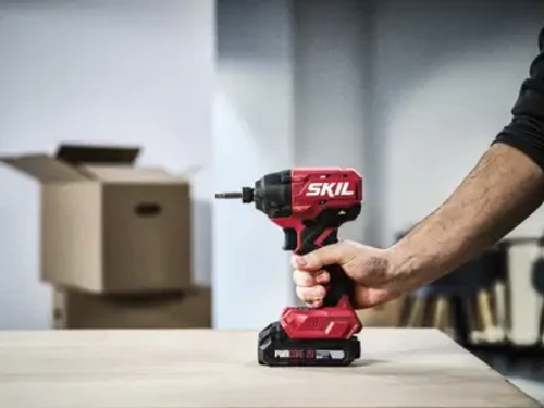מברגת אימפקט SKIL 20V בשימוש על שולחן עבודה, כלי קומפקטי וחזק לעבודות הרכבה והברגה