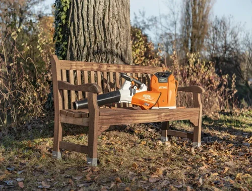מפוח עלים נטען STIHL BGA 200 מונח על ספסל בגינה, מפוח ידני מקצועי לניקוי עלים ופסולת