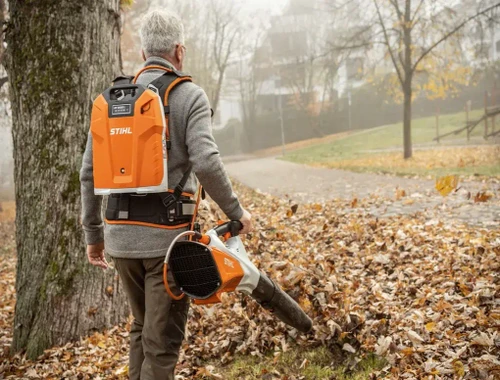 מפוח עלים נטען STIHL BGA 200 עם סוללת גב בשימוש לניקוי עלים בפארק, מפוח אלחוטי מקצועי לעבודות גינון