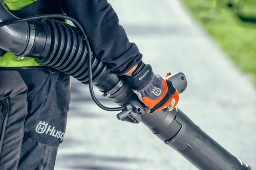 ידית שליטה וצינור אוויר של מפוח גב Husqvarna מקצועי בזמן עבודה עם מפוח עלים בנזין לניקוי שבילים ושטחים ציבוריים