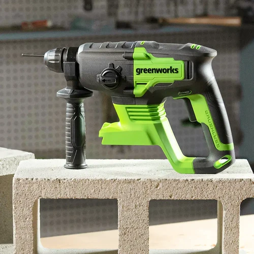 פטישון אלחוטי Greenworks GD24SDS2 24V ללא פחמים מונח על בלוק בטון ומיועד לעבודות קידוח מקצועיות