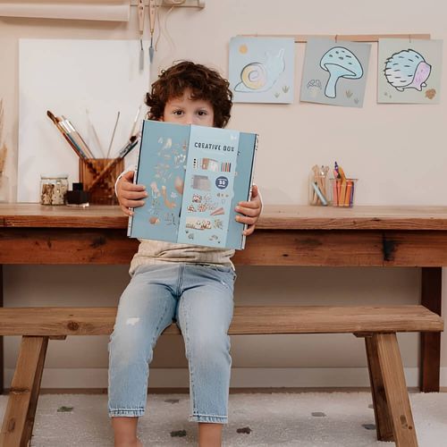 ילד יושב בחדר ובידיו קופסת ערכת יצירה - ערכת יצירה קריאייטיב בוקס - Little Dutch