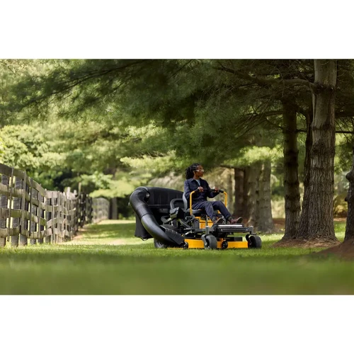 טרקטורון כיסוח דשא Zero-Turn דגם Cub Cadet ULTIMA Z3-60 בפעולה על מדשאה רחבה לצד עצים וגדר עץ