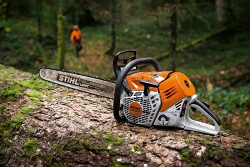 מסור שרשרת STIHL MS 500i מונח על גזע עץ ביער עם להב STIHL LIGHT 04