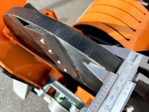 תקריב סכין החיתוך של מרסקת גזם DELEKS DK900, עם קליבר למדידת עובי הלהב ומנגנון הריסוק המתכתי