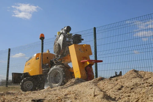 גרינדר גדמים מקצועי LASKI F 500 HR בפעולת כרסום בשטח פתוח, ראש כרסום מסתובב המפזר שבבי עץ ומערכת שליטה מרחוק