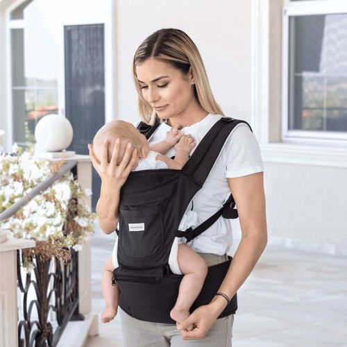 אישה נושאת תינוק במנשא Chloe, בתנוחת פנים אל פנים, המאפשרת הנקה נוחה.